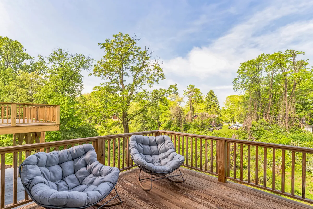 This image focuses on two comfortable chairs on a wooden porch, surrounded by lush greenery. The seating area provides a peaceful space for relaxation, reading, or enjoying Asheville’s natural surroundings. The view is intimate and connected to the outdoors, showcasing an ideal spot for unwinding after work or taking a thoughtful break.