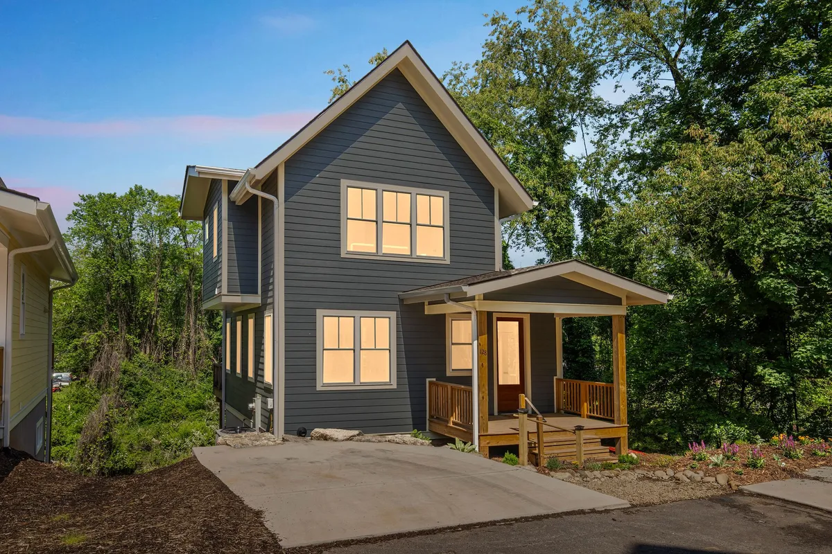 A welcoming exterior view of the home featuring a spacious front porch with large windows and abundant surrounding greenery. The porch looks inviting for family gatherings, relaxation, or enjoying sunsets, while the greenery hints at a peaceful, family-friendly neighborhood.