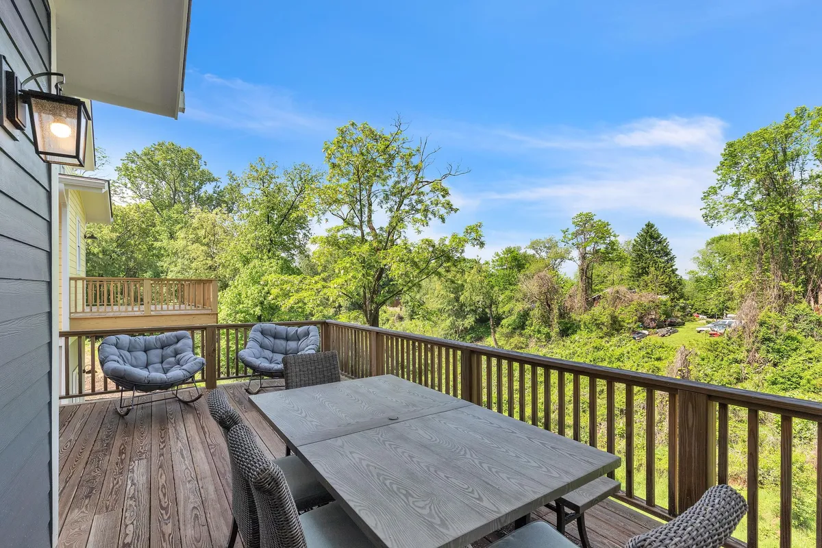 A tranquil outdoor dining area set amidst lush greenery, featuring a spacious table and comfortable seating. The scene captures the essence of al fresco dining with views of surrounding nature, inviting guests to relax, socialize, or enjoy meals outdoors. The area is bathed in gentle natural light, highlighting a strong connection to the outdoors.