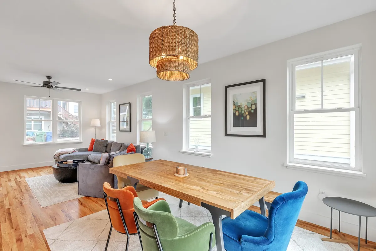 A bright, open dining space with a large table, colorful chairs, and a statement chandelier. The room is designed for family meals, game nights, or casual gatherings, radiating warmth and togetherness.