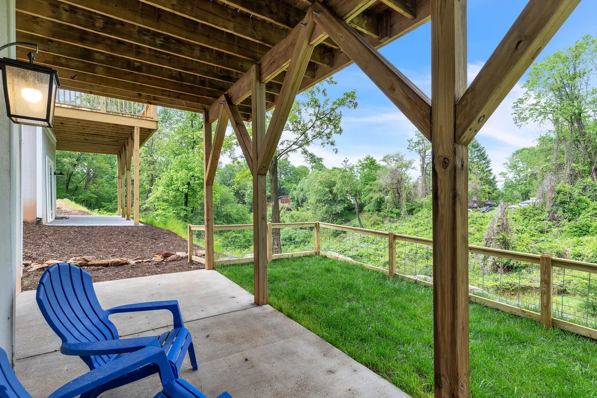 A peaceful porch scene with blue chairs set on a wooden structure, overlooking a green landscape. The setting is ideal for relaxing, listening to nature, or watching sunsets. The open air and natural surroundings evoke the tranquility and beauty of Asheville’s outdoors.